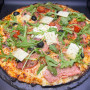 ITALIENNE : Sauce tomate maison, mozzarella 100 %, jambon blanc, olives, tomates cerises, roquette, Comté AOC, origan.
