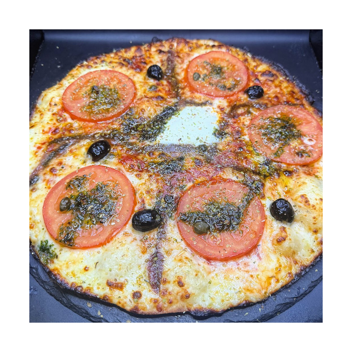 NAPOLITAINE : Sauce tomate maison, mozzarella 100 %, rondelles de tomate, anchois, câpres, olives, origan.